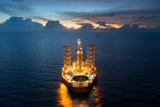Aerial view of jack up drilling rig in the middle of the ocean while rig move at night time Aerial view of jack up drilling rig in the middle of the ocean while rig move at night time oil derrick crane crane exploration stock pictures, royalty-free photos & images