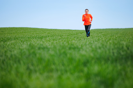 Running on green meadow in spring, fit and healthy people