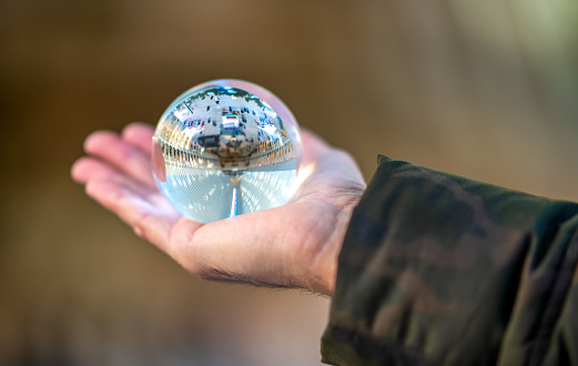 Woman hold a Crystal Ball with modern building interior and hall reflection.