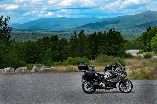 Randolph, NH, USA – July 16, 2022.  A BMW sport touring motorcycle is parked at a scenic overlook in the White Mountains of New Hamshire near Mt. Washington; an iconic spot for viewing this Granite State mountain range.  Beautiful summer day with blue skies and white clouds.