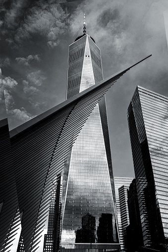 New York, NY, USA – October 28, 2018.  A black and white image of The Freedom Tower standing behind The Oculus on the site of the original World Trade Center buildings in NYC (New York City) in lower Manhattan in New York. A dramatic sky background highlights the image of this iconic structure.