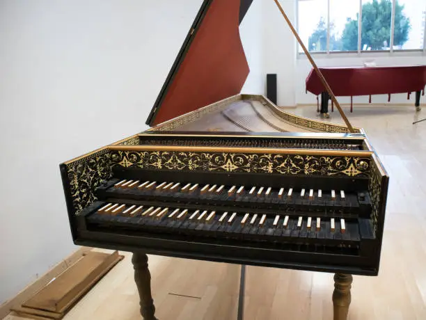 front view of a harpsichord, baroque instrument keybord with black wooden keys, middle ages piano