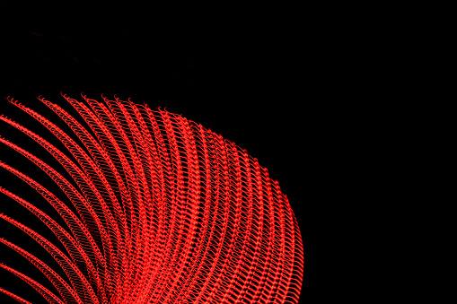 An abstract image of a red egg-shaped abstract image.  There are layers of light peeling off of it. The light painting image represents digital connections.  .
