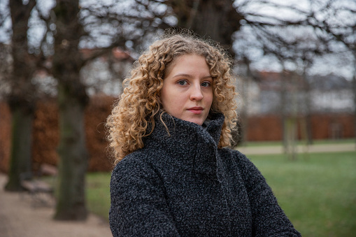 Portrait of a young girl with curly hair in a public park on a winter day