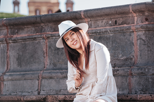 A portrait of a pretty woman smiling outside on a sunny day wearing a sun hat during the summer.  Room for copy space.