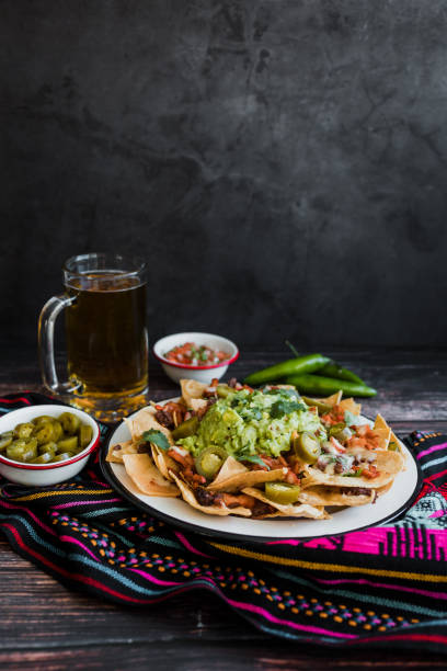 nachos mexicanos com queijo ou chips de tortilha com carne, abacate e cerveja, comida tex mex na américa do méxico - chili pepper guacamole food beer - fotografias e filmes do acervo