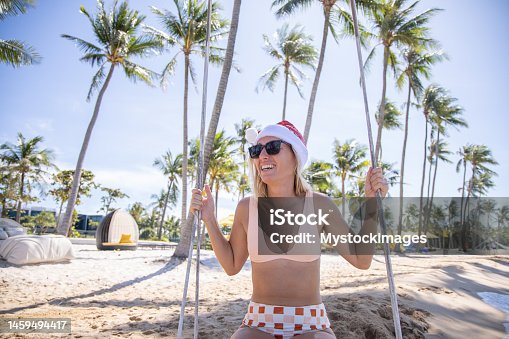 istock Woman on vacation in luxury resort swinging with Christmas hat 1459494417