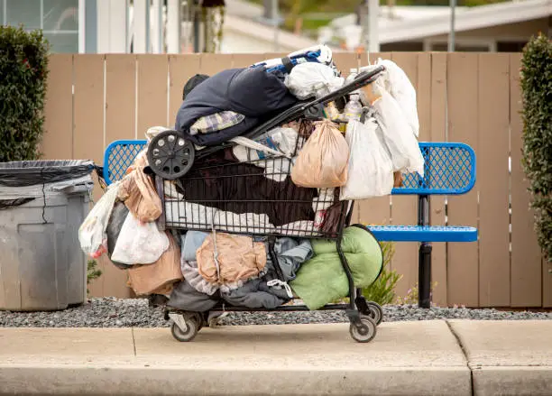 Homeless persons belongings in a shopping cart in a sidewalk