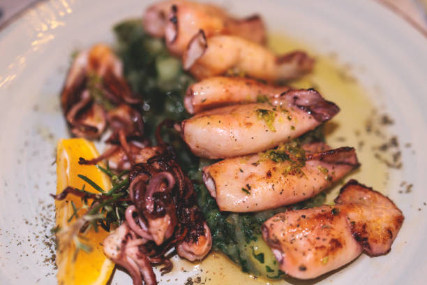 istock Fried grilled baby squids on a plate with garlic, lemon and mashed potato garnish served in a traditional seafood restaurant in Montenegro, prepared cooked calamari on a table 1459499275