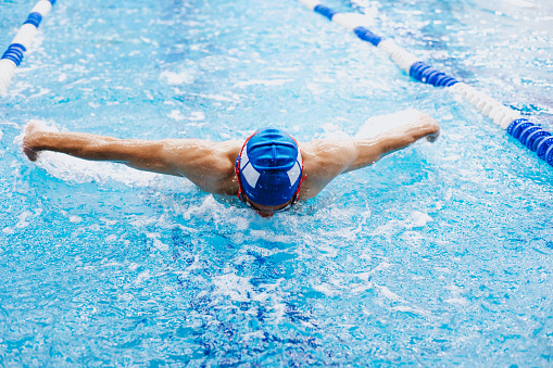 Professional female swimmer swimming the front crawl stroke. Freestyle competition concept.