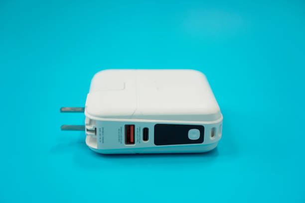 istock Image shows a white backup battery with a charging cable connected to a device on a blue background, close-up, isolated. 1459503657
