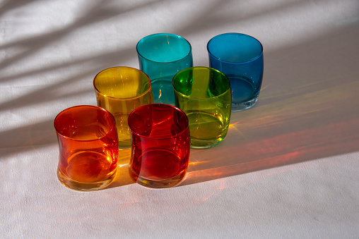 Multicoloured glasses with shadows on white background.