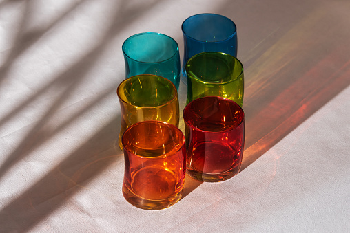 Multicoloured glasses with shadows on white background.