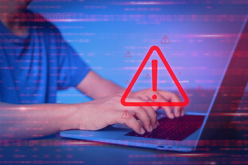 Man used computer for working. Virtual security warning system hacked alert on laptop screen. Cybersecurity vulnerability on internet, virus, data breach, malicious connection. Selective focus.