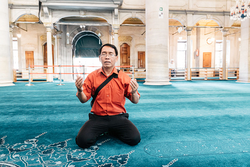View Of  senior man Praying While Kneeling At Mosque