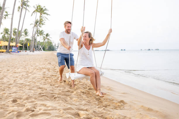 istock Playful young couple on tropical beach using swings at sunrise 1459519228