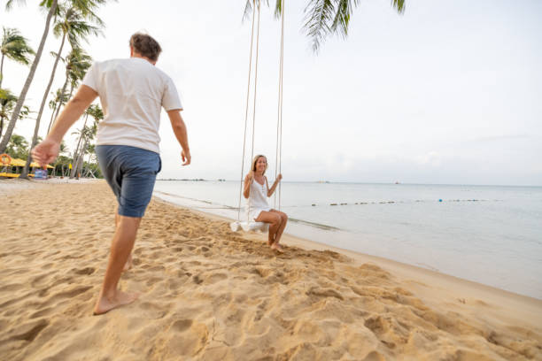 istock Playful young couple on tropical beach using swings at sunrise 1459519309