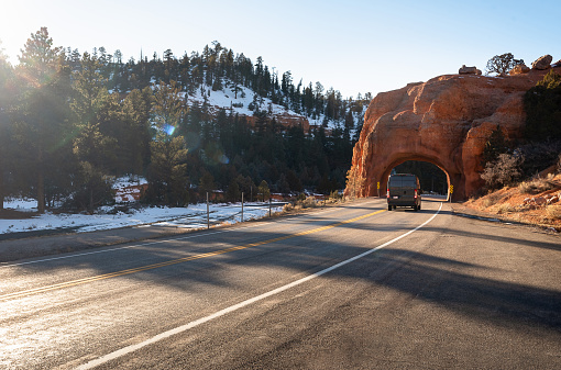 Van going through a natural tunnel made of red rock in near Bryce Canon in Utah