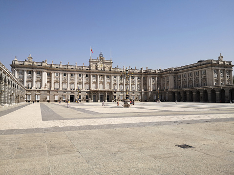 Tourists walking on the large Plaza de Armeria at the Palacio Real in Madrid, Spain.