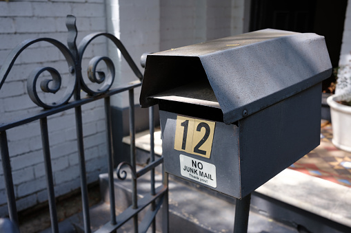 Black metal mailbox on a pole. No junk mail sign attached.