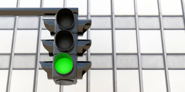 istock Hanging Traffic Light with green go signal on skyscraper background. Under view. 3d render 1459525911