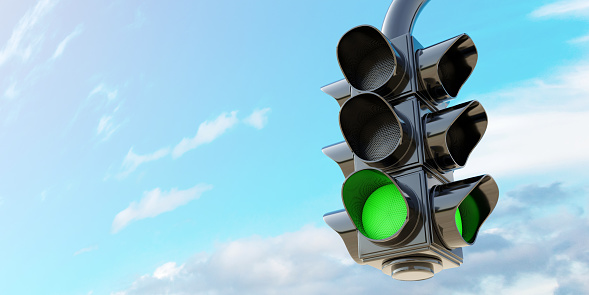 Safety travel on road concept. Traffic Green Light, hanging semaphore with green go signal on cloudy blue sky background, space for text. 3d render