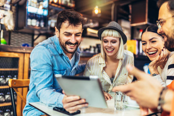 istock Young friends looking at digital tablet while sitting in cafe. 1459533725