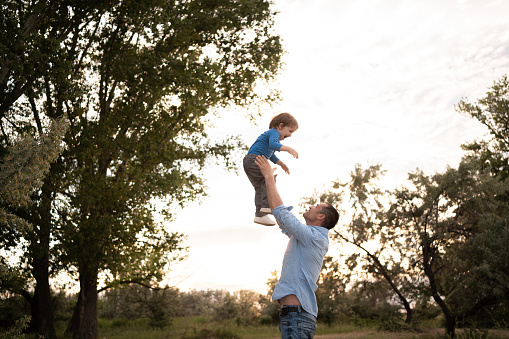 Happy joyful child, father fun throws up son in the air, carefree, family, travel vacation childhood, father's day. Sunlight on the sunset. Summertime concept