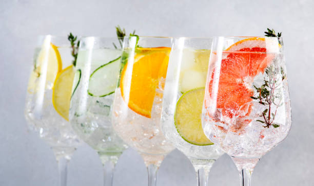 istock Gin tonic citrus cocktails set. Alcoholic drinks in wine glass with lime, lemon, grapefruit, orange, soda and herbs, gray background. Summer cocktail party. Close-up banner 1459534455
