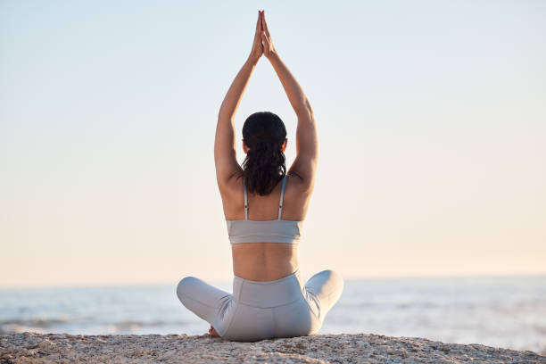 yoga, bewegung und meditation am strand mit einer frau in gebetsposition für zen, ruhe und gleichgewicht, während sie chakra-training für den frieden macht. weiblich am meer für achtsamkeit und spirituelles training - wohlbefinden stock-fotos und bilder