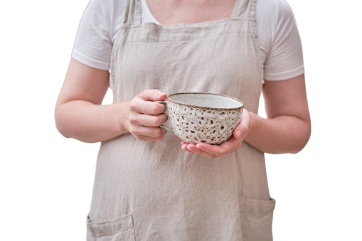 A large cup is in the hands of a woman in the kitchen, isolated on a white background. Female hands holding a cup for coffee or tea