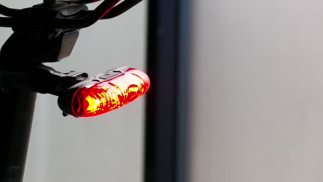 Flashing LED red taillight mounted on a bicycle close-up in the daytime. The back of the bike with a red frame warning light