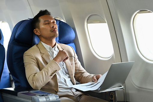 Tried businessman distracted from computer work during business travel. Business or travel abroad concept.