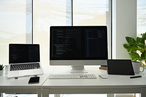 Computer Monitors With Programming Code On White Office Desk At ...
