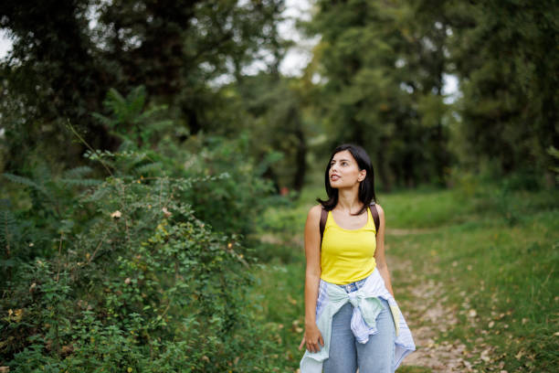 Happy young woman walking in green nature on sunny day