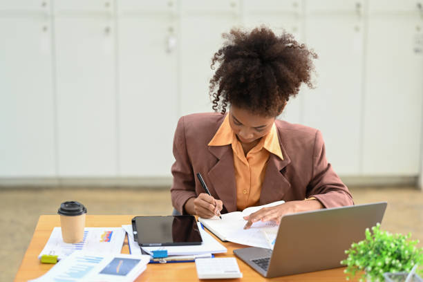 istock Focused female accountant comparing corporate income for previous year with current one at her workstation. 1459547574