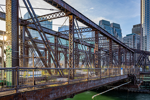 Cityscape of an old abandoned truss bridge in the bay on the modern Boston waterfront combined with urban new glass skyscrapers and colonial bricks buildings in Massachusetts in New England