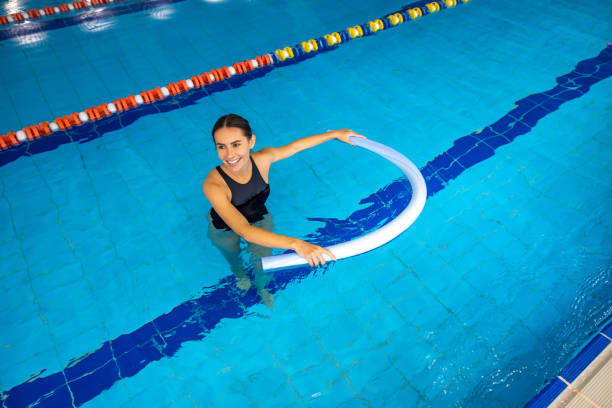 istock Smiling young woman doing exercises with float noodle 1459549267