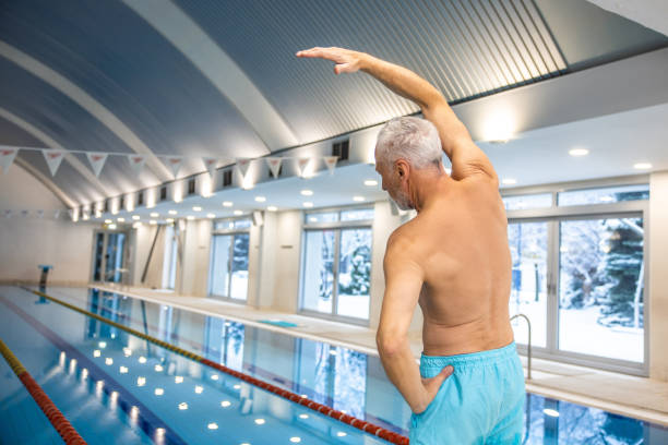 istock Mature man in blue swim shorts doing warming up stretching 1459550667