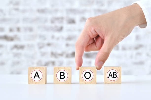 human's hand picking up wooden blocks with blood type alphabet - bloedbank stockfoto's en -beelden