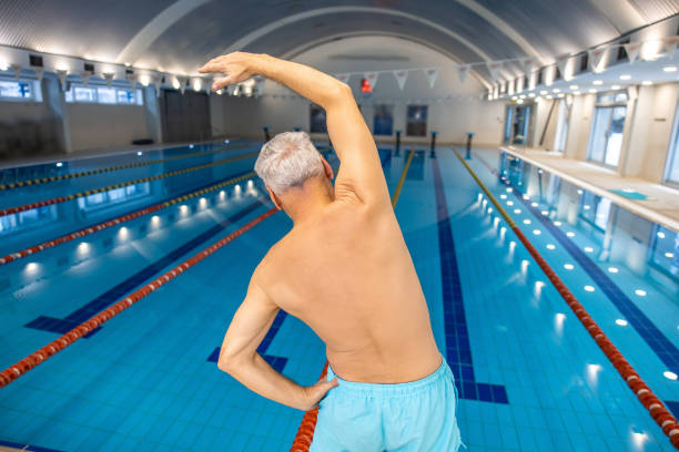 istock Mature man in blue swim shorts doing warming up stretching 1459550818