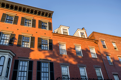 An classic colonial multistory red brick apartment strict geometric shape building with living quarters in the attic and forged balconies in the Cambridge city limit in Massachusetts in New England