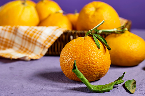 Fresh ripe mandarine in basket near purple background