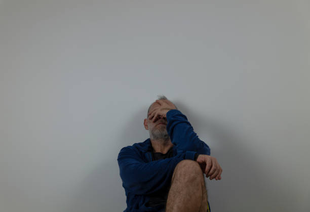 istock Adult man sitting on floor against white wall 1459558426