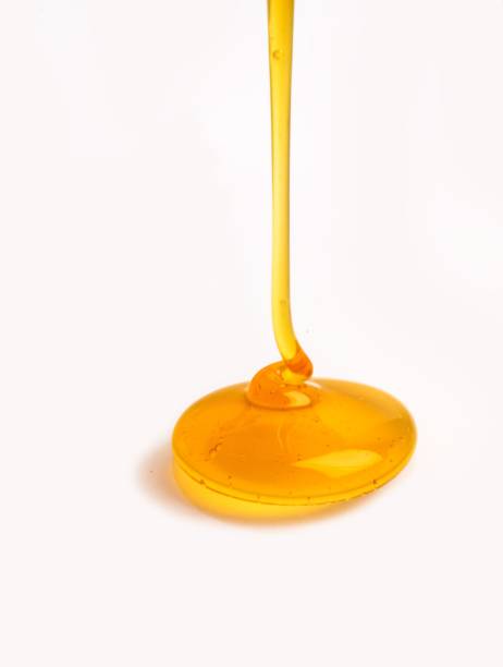 istock Vertical closeup of honey dripping on a white background 1459558742