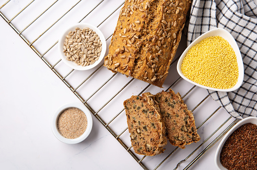 Gluten Free Homemade Bread. Healthy eating, dieting, balanced food concept. Cereals gluten-free (millet, buckwheat), psyllium husks, flax seeds, sunflower seeds on gray marble background.
