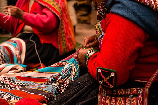 A closeup shot of Peruvian women working on beautiful handmade textiles