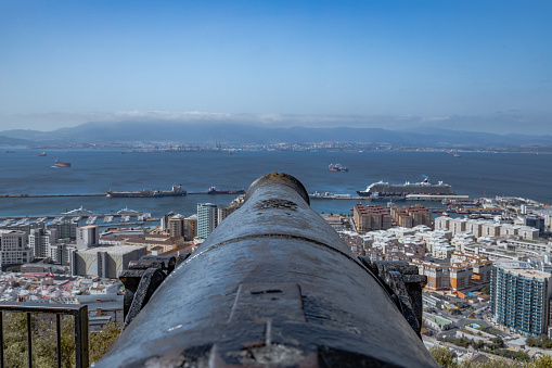 An old cannon aimed at the Bay of Gibraltar full of ships. Incredible skyline, blue sky with amazing clouds.