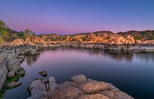 Scenic Watson Lake Prescott in Arizona during a purple sunrise with rocky mountains in the background