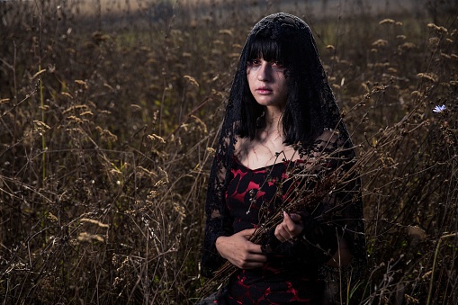 A scary mourning woman with bangs in a black dress - the concept of Halloween